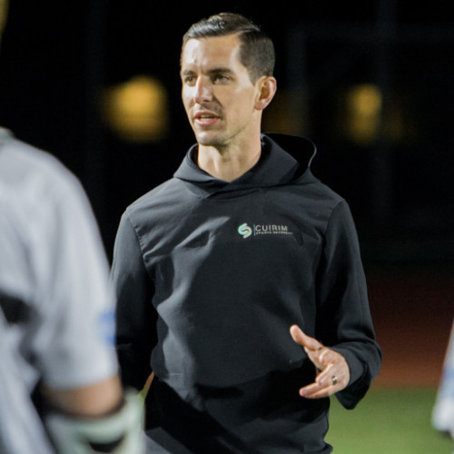 man wearing black hookie looking just off the camera on a sports pitch at night