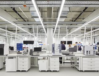 inside the labs of AstraZeneca's Discovery Centre by Herzog de Meuron showing their workstations and a group of people having a conversation