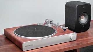 Victrola Stream Sapphire sitting on a rack with KEF speaker