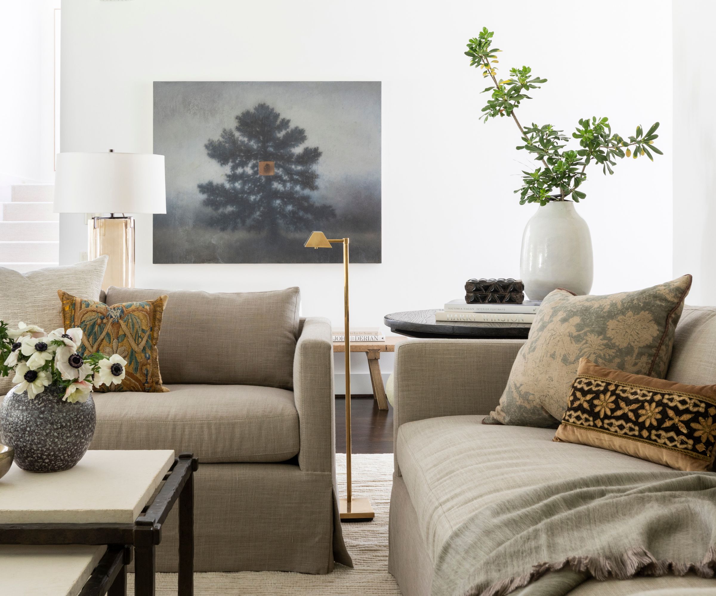 neutral living room with two linen taupe sofas, a metal and stone coffee table, with mismatched pattern throw pillows