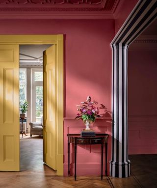 open plan space with deep pink walls zones with striped black and white paint on the woodwork