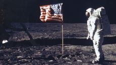 Astronaut on moon next to American flag.