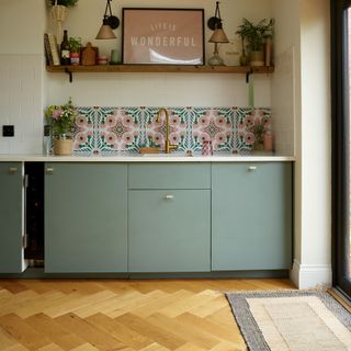 Green modern kitchen with door mat next to back doors.