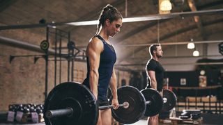 a photo of a man and woman in the gym holding a barbell: Romanian deadlift