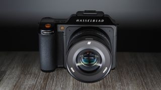 a Hasselblad X2D on top of a wooden table, under a spotlight
