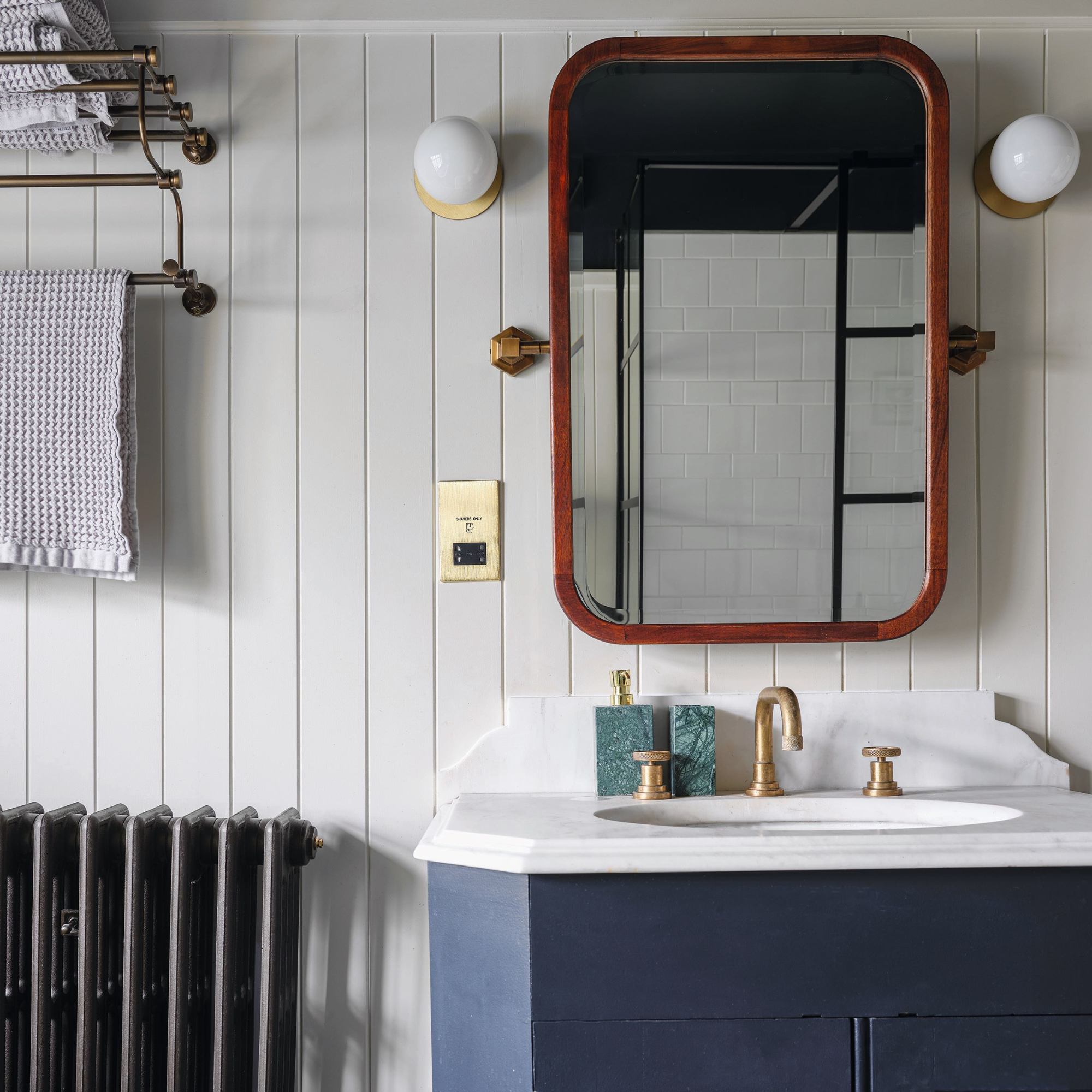 Handbasin with white and grey marbled top, blue vanity unit, wood panelled wall and original cast iron radiator