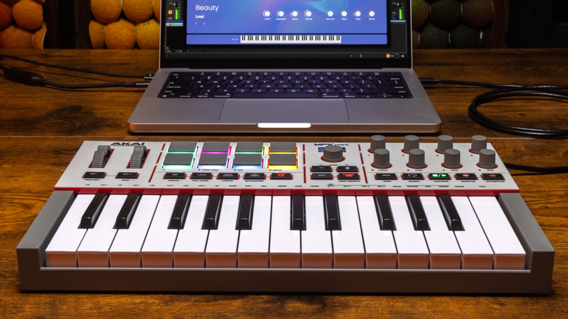 An Akai MPK Mini IV MIDI keyboard on a desk with a laptop