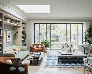 living room furniture arranging mistakes, neutral living room, crittall doors view of garden, armchairs and couches, large coffee table, rug, bookcases, skylight