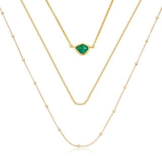 three gold chain necklaces with one green charm