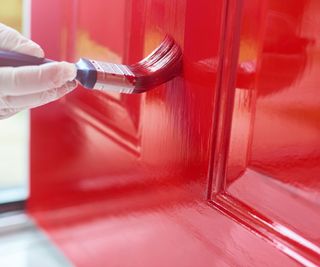 Someone painting a door using a brush