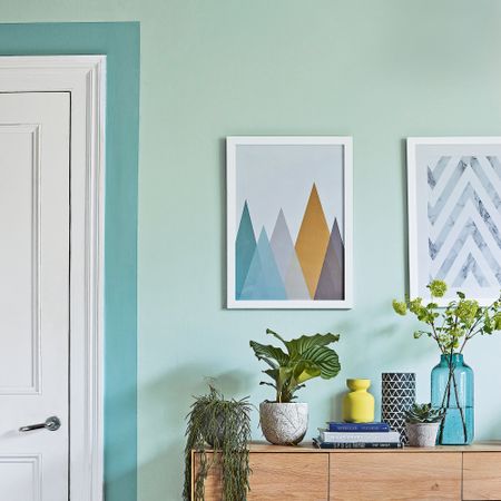 Internal door surrounded by green paint border beside console table with houseplants