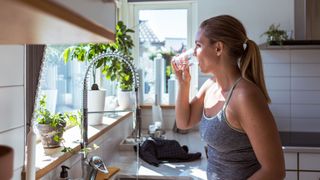 Woman drinking water from the sink, representing what happens when you're working out but not losing weight