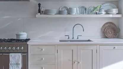 A stainless steel kitchen sink set into white countertops