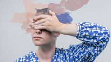 Woman's hands over eyes with paint splatters, representing what does perimenopause feel like
