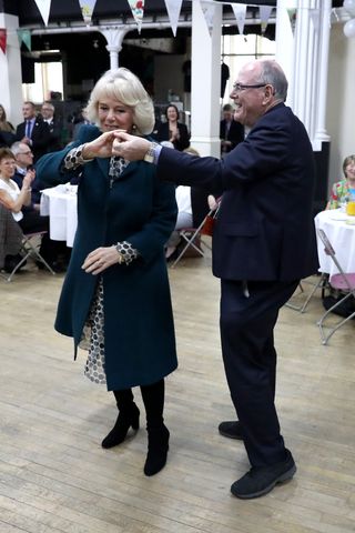 Queen Camilla dancing with Arthur Edwards at a 2017 tea party as people watch on at tables