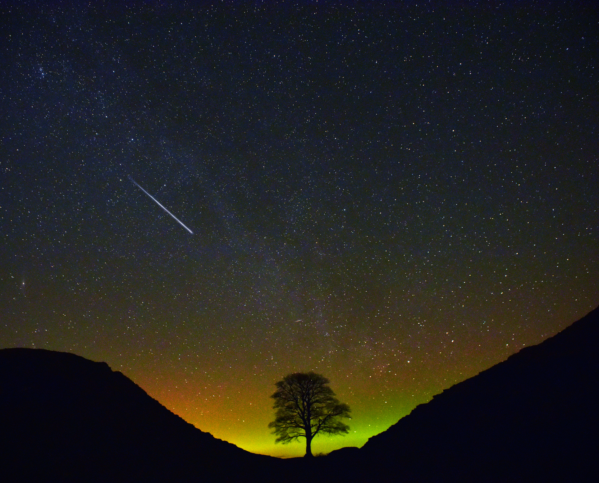 A meteor streaks across the night sky at Sycamore Gap in Northumberland.