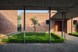 Exterior of Rajiv Saini's Dhampur House showcasing the brick structure and sheltered gardens