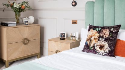 Bed with grey upholstered headboard and wooden bedside table