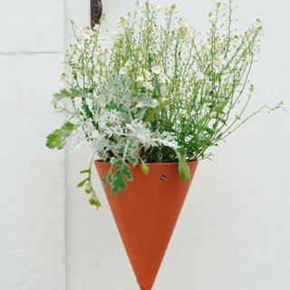 terracotta hanging plant holder with white flowers planted in and green and white leafy plant