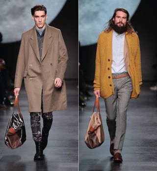 Two men are walking down a runway during a fashion show.