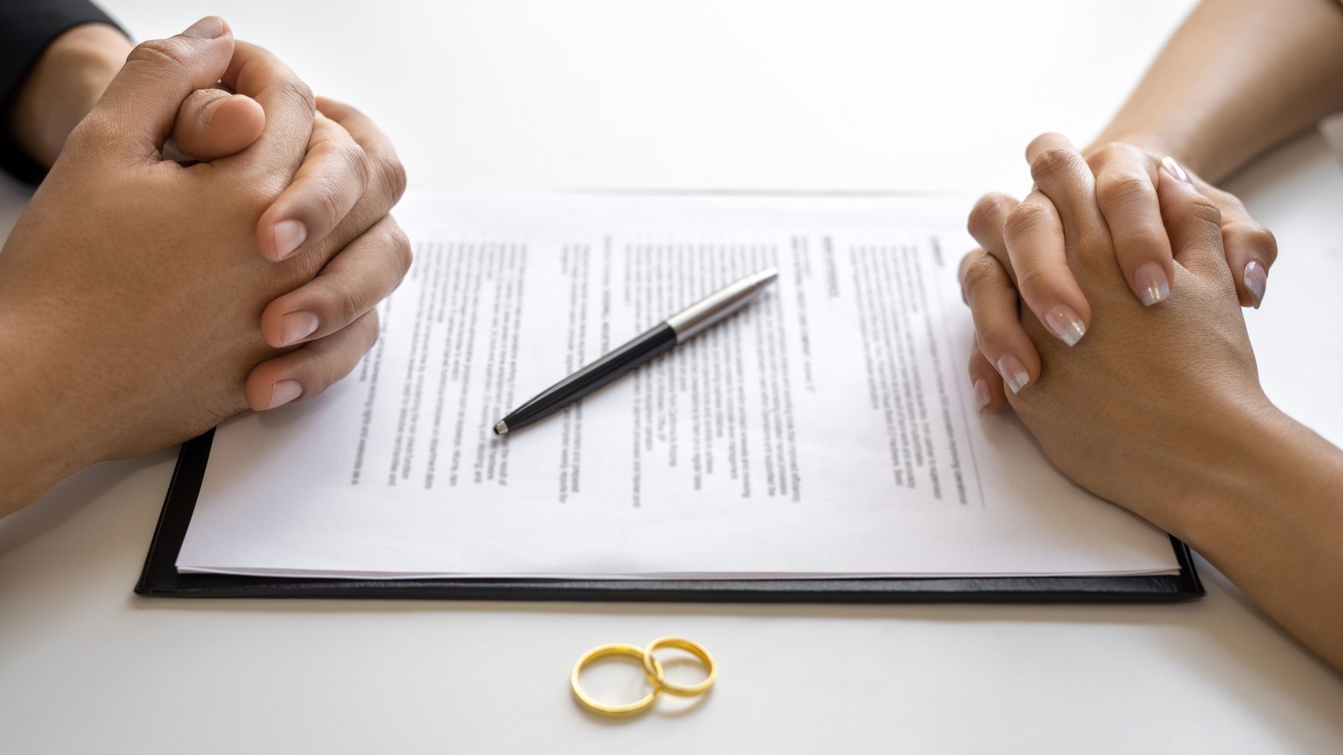 Two pairs of hands clasped over divorce papers