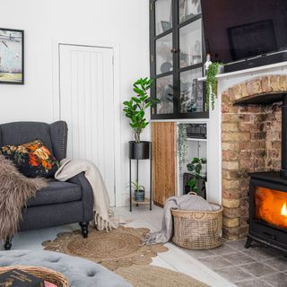 Living room with stove style fireplace, cabinet storage, single armchair with cushions and throws