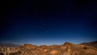 view of Ursa Major in the night sky above a rocky terrain. 