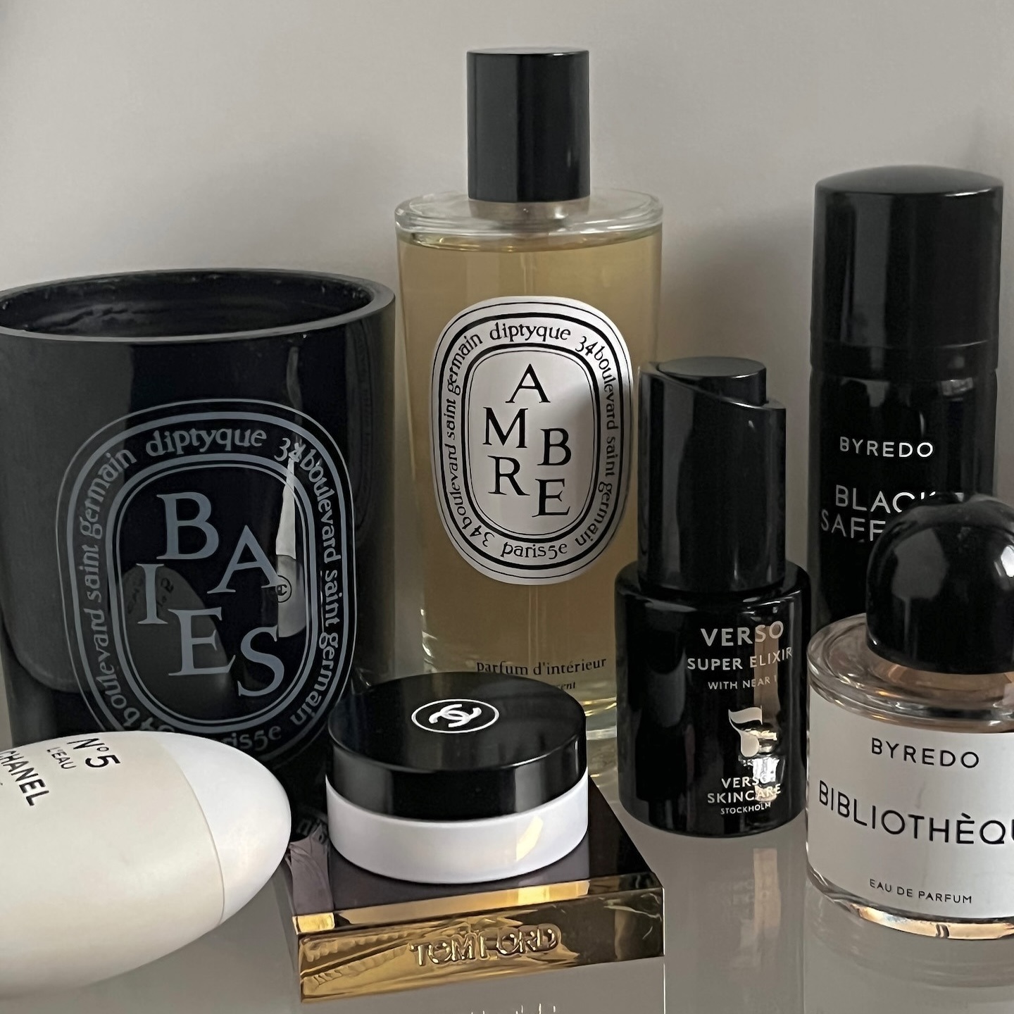 a Diptyque candle and fragrance surrounded by Chanel and Byredo products