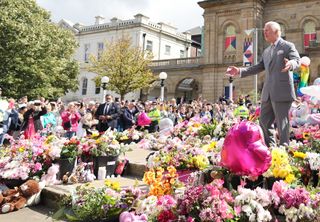 King Charles III reacts as he views the floral and balloon tributes for the victims of the Southport stabbings outside Southport Town Hall during his visit to meet local community and emergency services on August 20, 2024 in Southport, England.