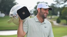 Scottie Scheffler smiles while holding the FedEx Cup over his shoulder