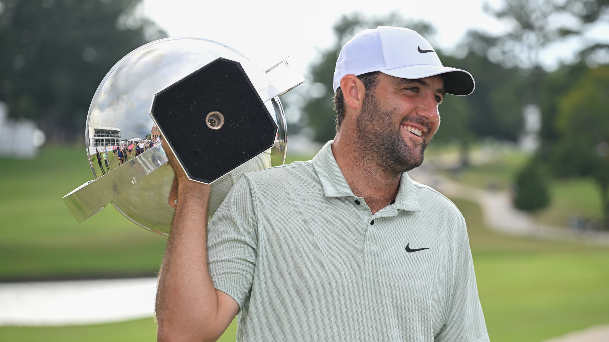 Scottie Scheffler smiles while holding the FedEx Cup over his shoulder