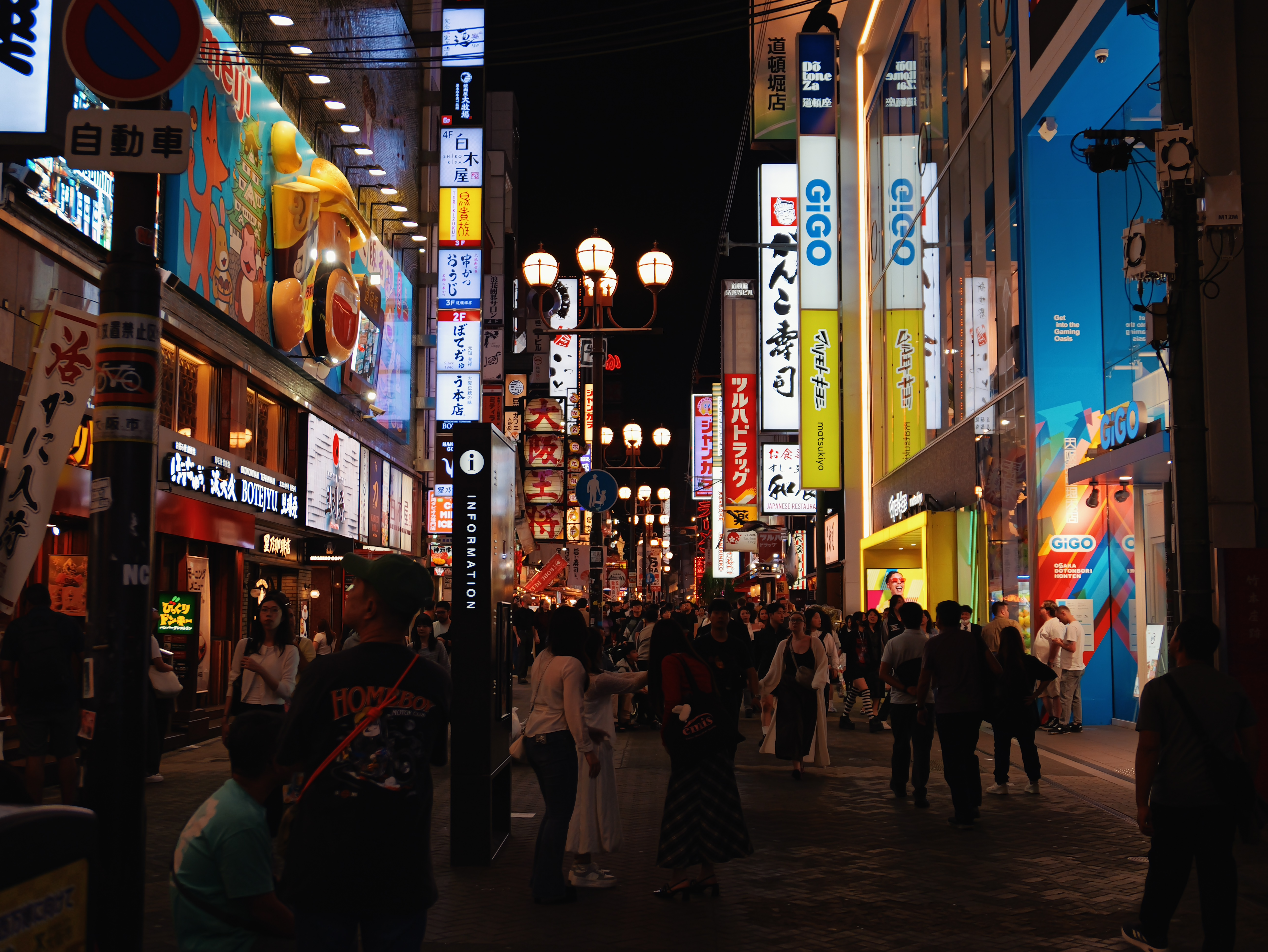 Busy Dotonbori street at night with illuminated shop signs.