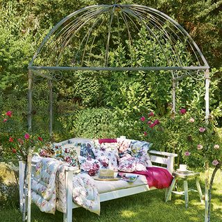 outdoor with old pergola and wooden sofa with cushions and floral print