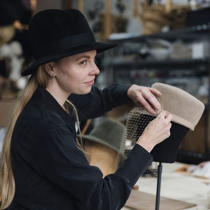 Hat-maker Gigi Burris attaching a veil to a felt cap