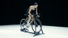 Wahoo KICKR ROLLR review: Pictured here, an athletic female cyclist riding a road bike mounted on the KICKR ROLLR