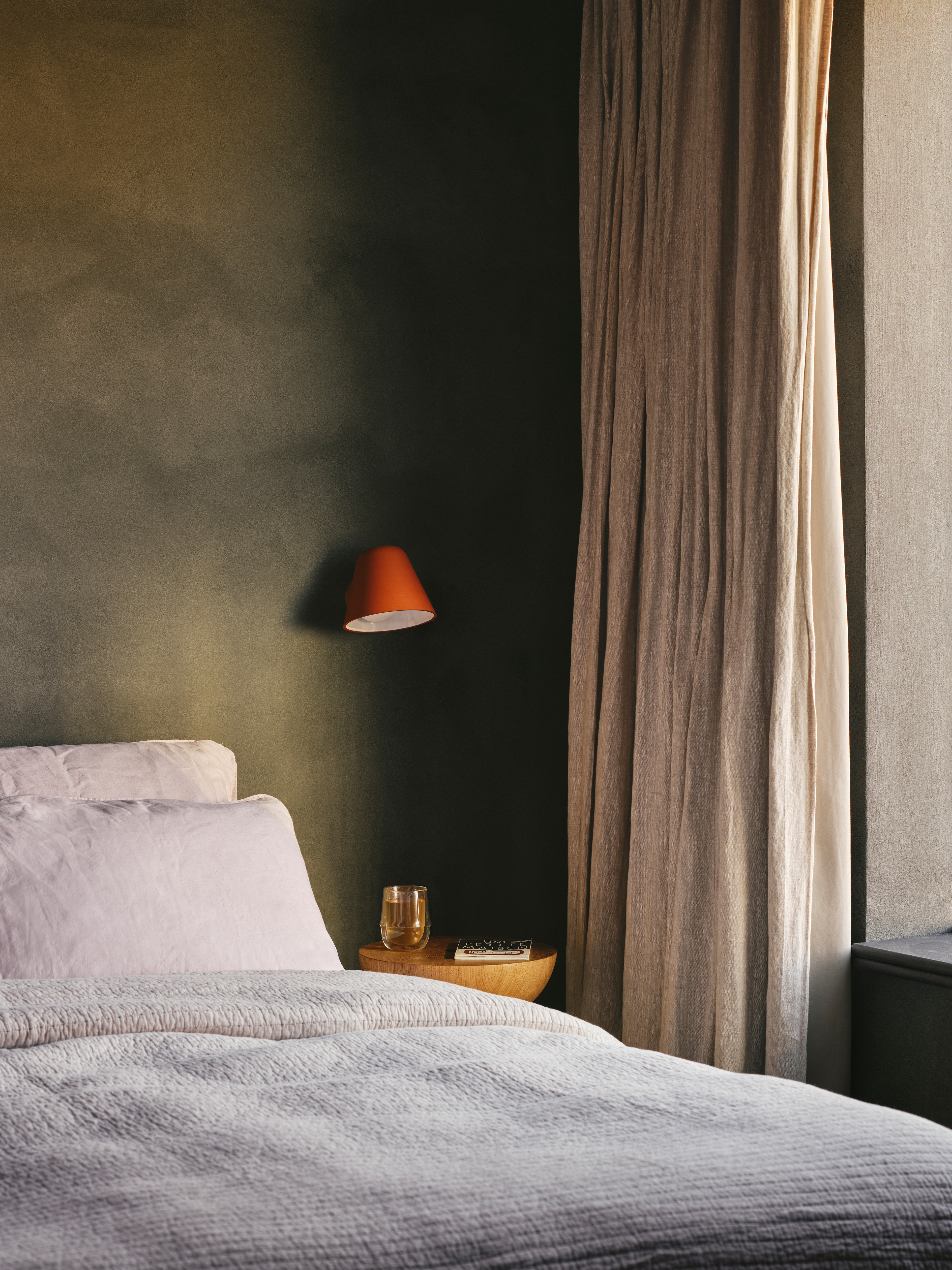 terracotta lamp on green wall in bedroom