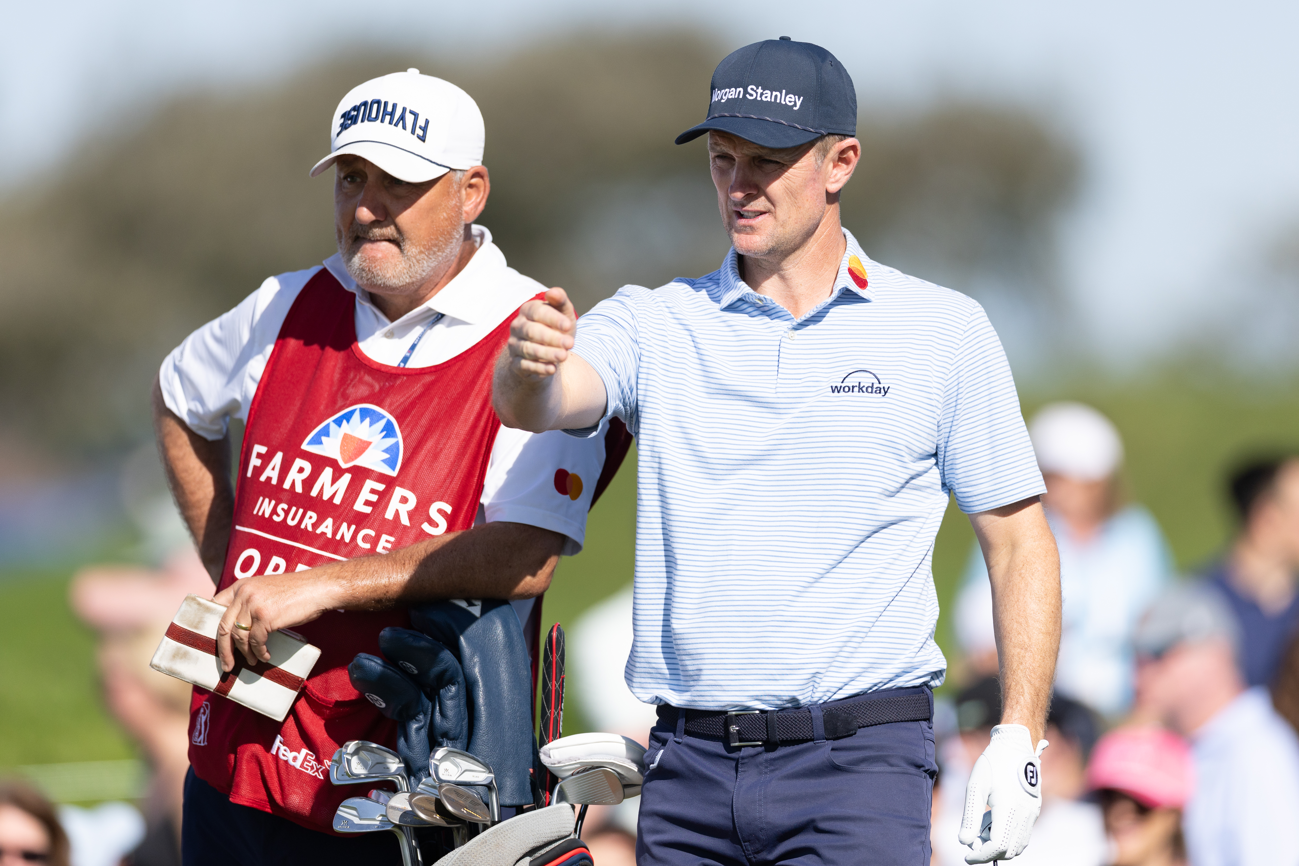 Justin Rose speaks to his caddie next to his golf bag
