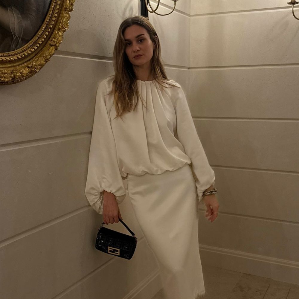 Influencer @annelauremais wears a satin dress with pointed-toe heels and a black clutch bag.
