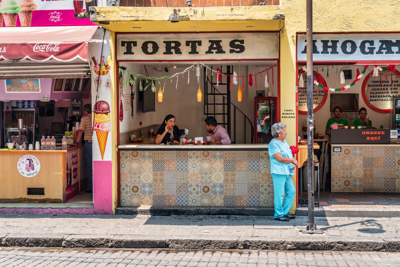 A series of sun-lit street photography shots of Mexico City portray a vibrant destination characterized by contrasting architectural styles, tropical plants, and bright colors.