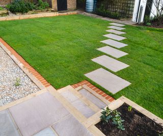 New turf installation around a new stepping stone pathway to a pebbled area and patio with steps. A