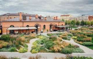 A brown building with awnings and gardens in front of it.