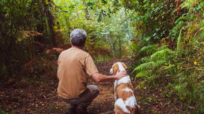 A man and his dog on a hiking trail.