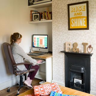 home office with fireplace and computer on desk with wallpaper on wall
