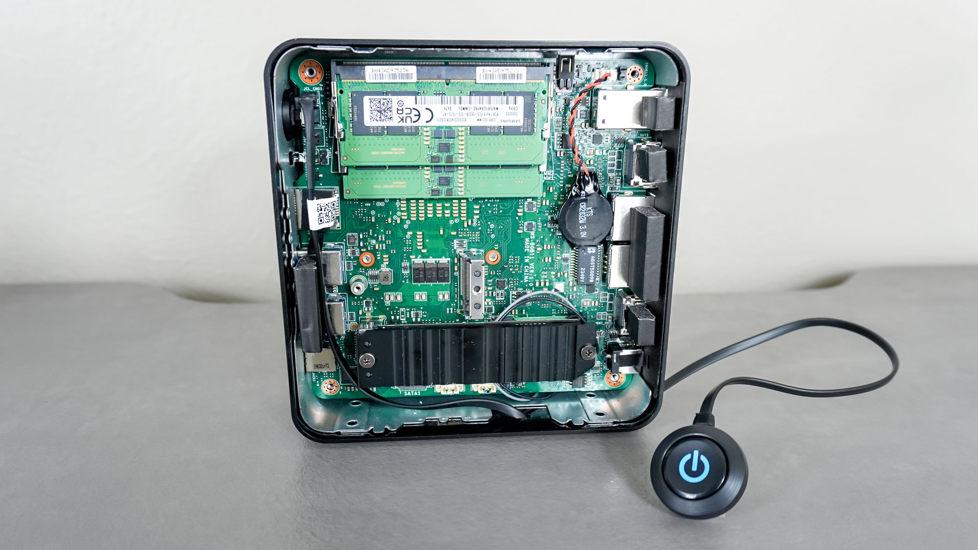 The MSI Cubi NUC 1M mini PC with its case open next to the included external wired power button MSI includes in the box