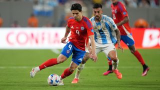 Víctor Davila of Chile, in a red shirt and blue shorts, plays the ball during match against Argentina.