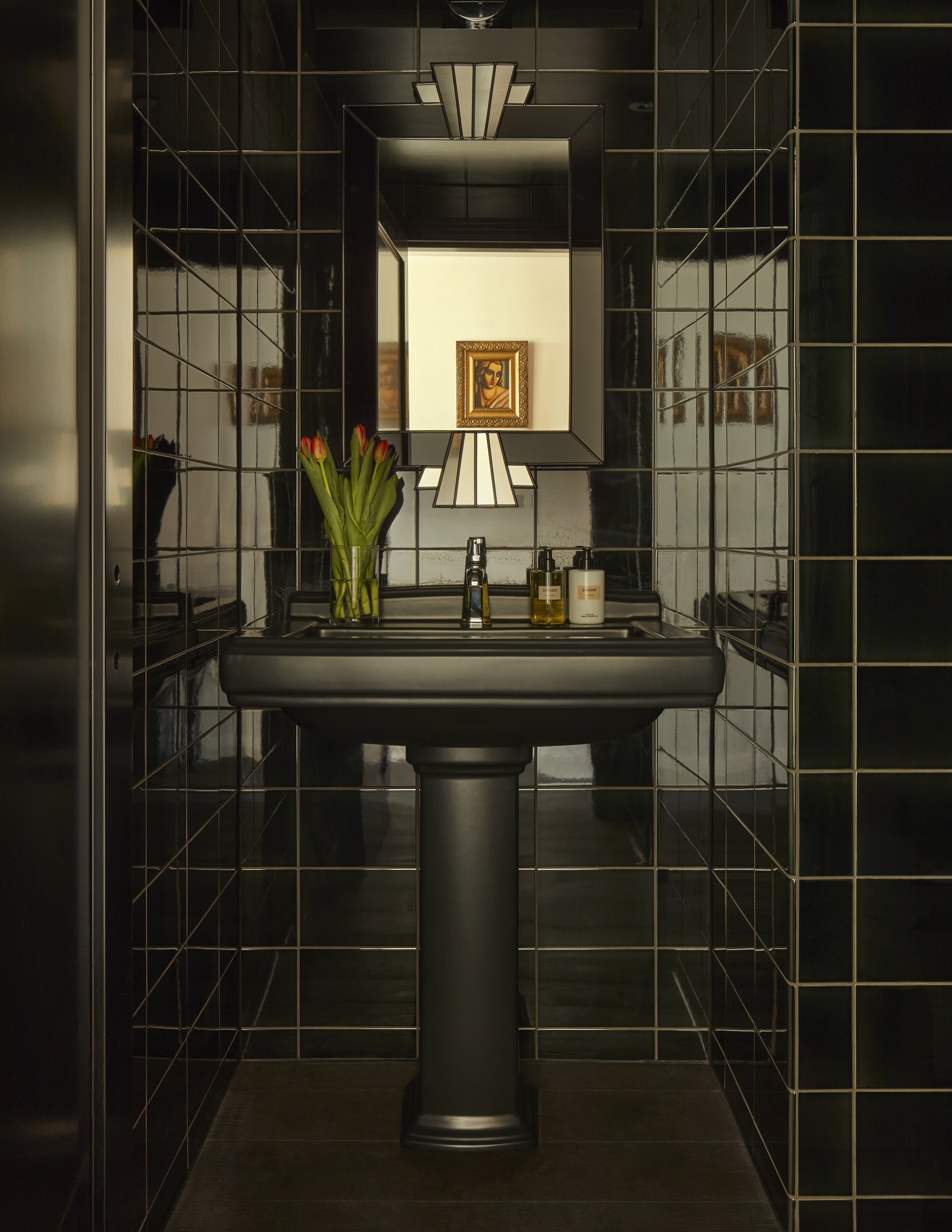 a black art deco bathroom with a black vanity and art deco mirror