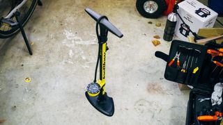 A yellow Topeak Joe Blow Sport III floor pump on a garage floor