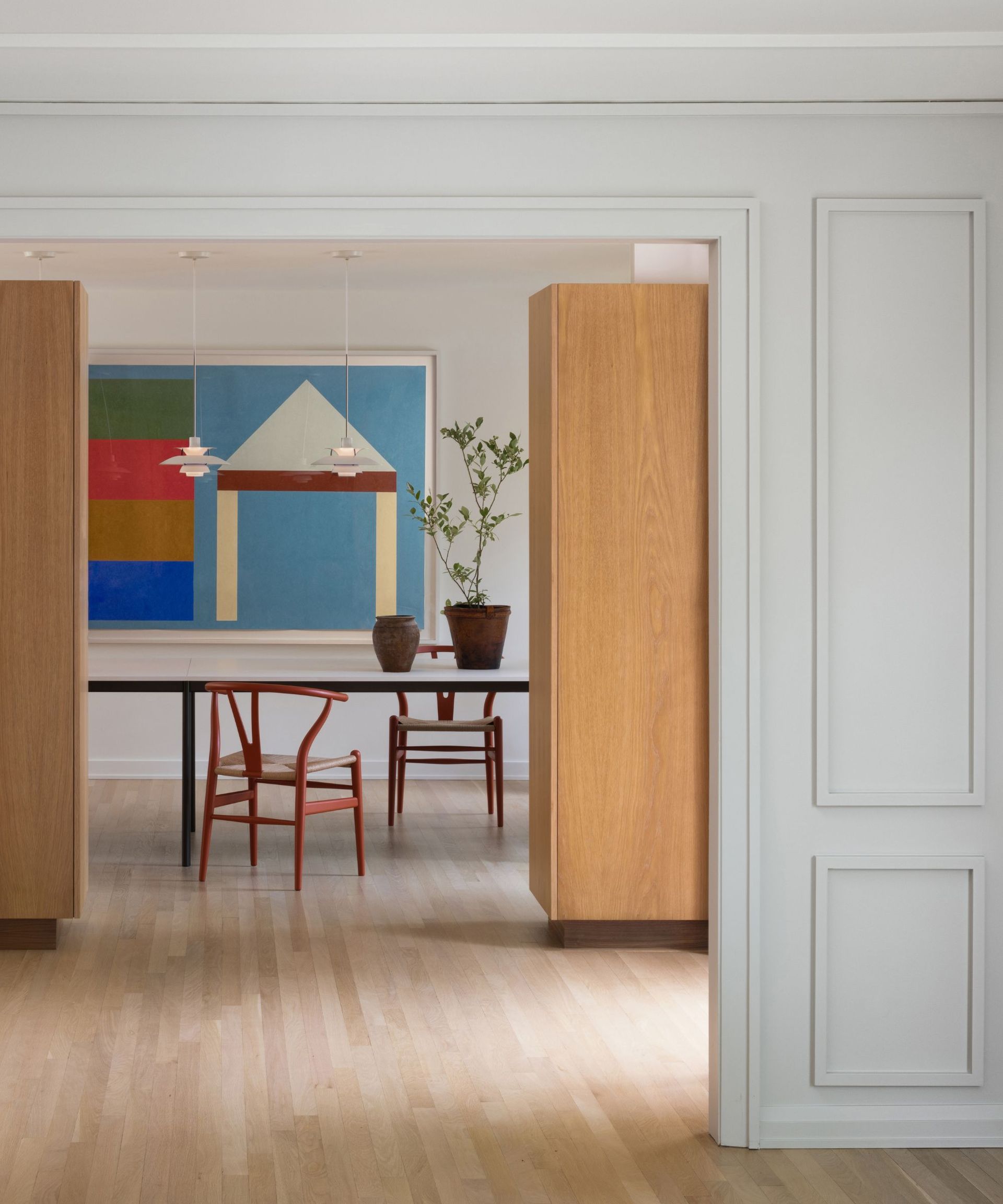 dining room with natural wood floor and bright colored artwork and chairs