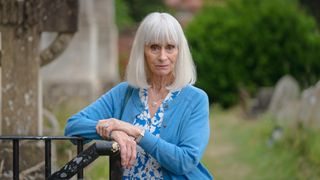 Rita Tushingham as Mrs Eddingham stands in a churchyard in The Marlow Murder Club.