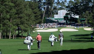 Jon Rahm, Brooks Koepka and their two caddies walk up the seventh hole at Augusta National during the Masters
